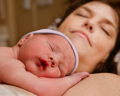 Photo of a woman resting with a newborn baby on her chest after giving birth, part of the bonding process