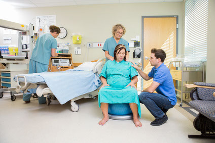 Photo of  a female in labour in a hospital room, partner giving support