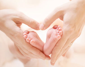 Mum's hands holding Baby's feet forming a heart shape with-in the image